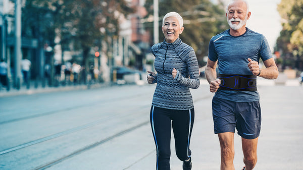 Senior man and woman jogging wearing TREK HEALTHY Cross-Pull Platinum Core and Back Support